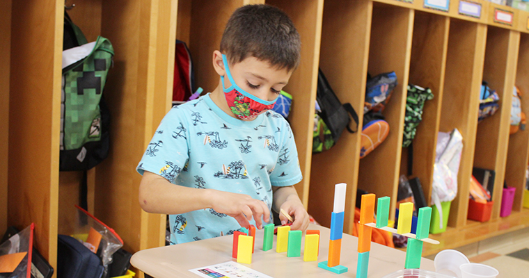 Masked student working with dominoes