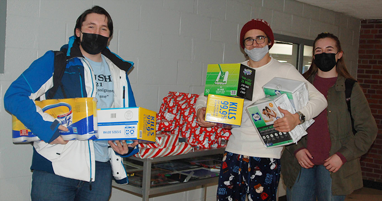 Three students holding donation items