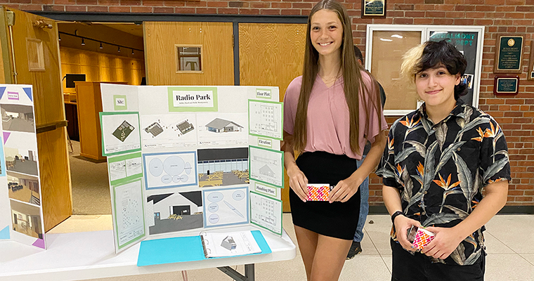 Two students posing with poster that reads "Radio Park"