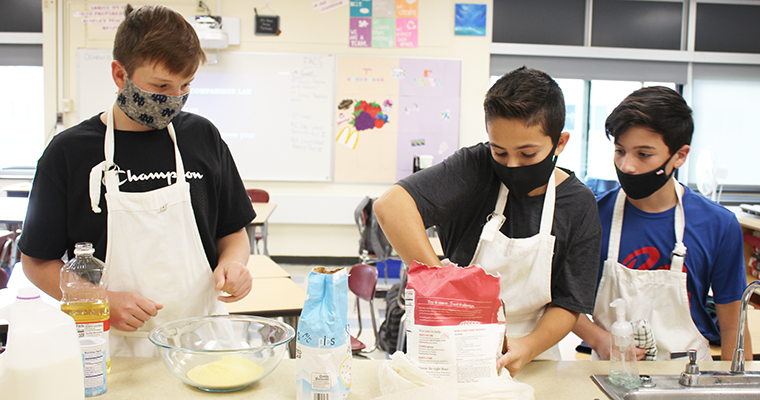 Three masked students baking