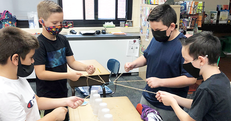 Four masked students working on a project