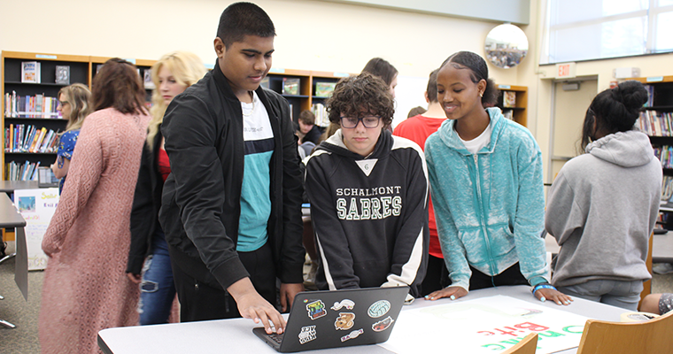 Three students looking over a computer