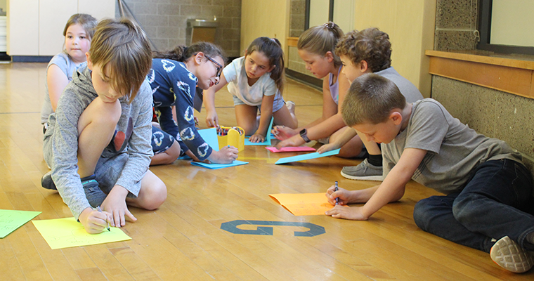 Students drawing on the gym floor