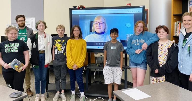 Students pose with smartboard display of author