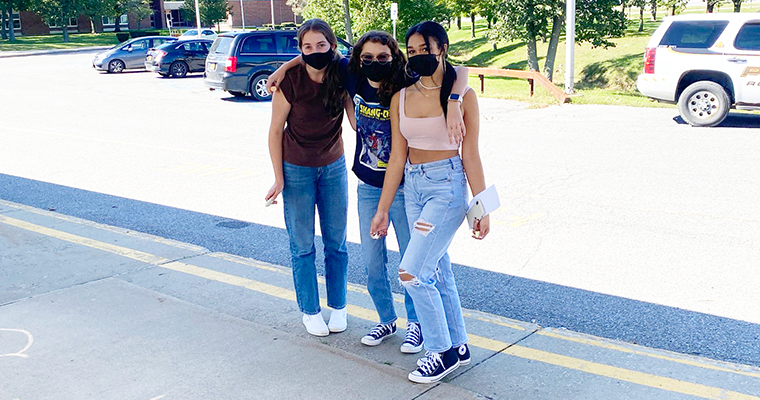 Three masked students posing outside