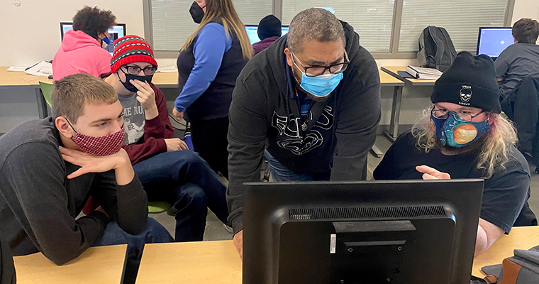 Three students and teacher looking at a computer screen