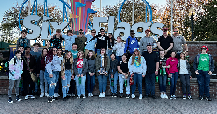 Wind ensemble poses in front of Six Flags sign