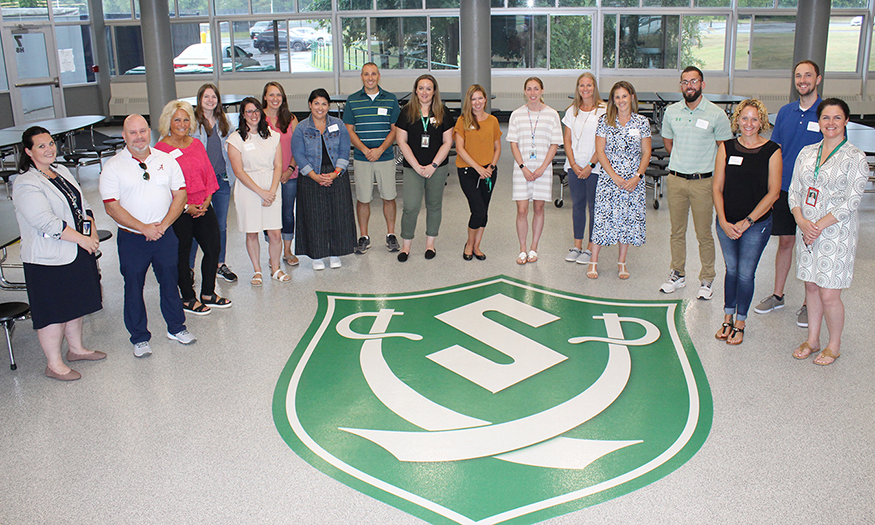 Group photo of new employees around Schalmont shield
