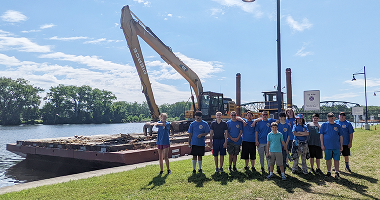 Students stand next to barge on river