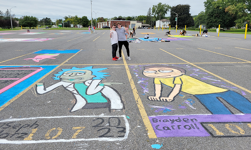 Students stand next to parking spaces they painted