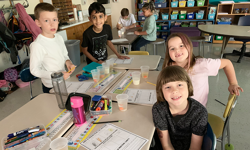 Students pose for photo at desk