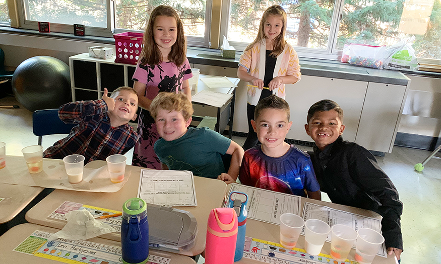 Students pose for photo at desk