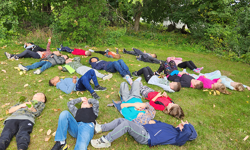 Students lay on ground during fall day