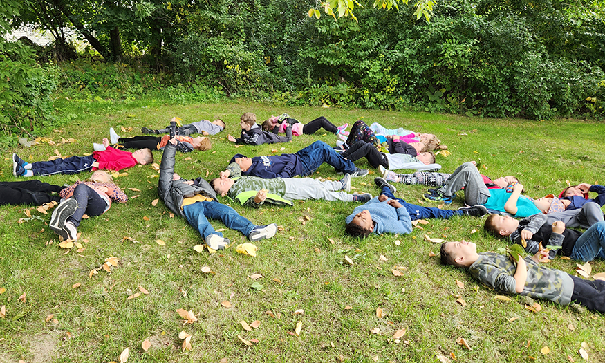 Students lay on ground during fall day