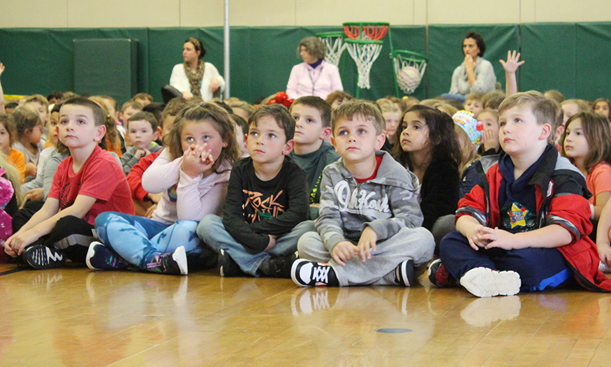 Students listen on gym floor