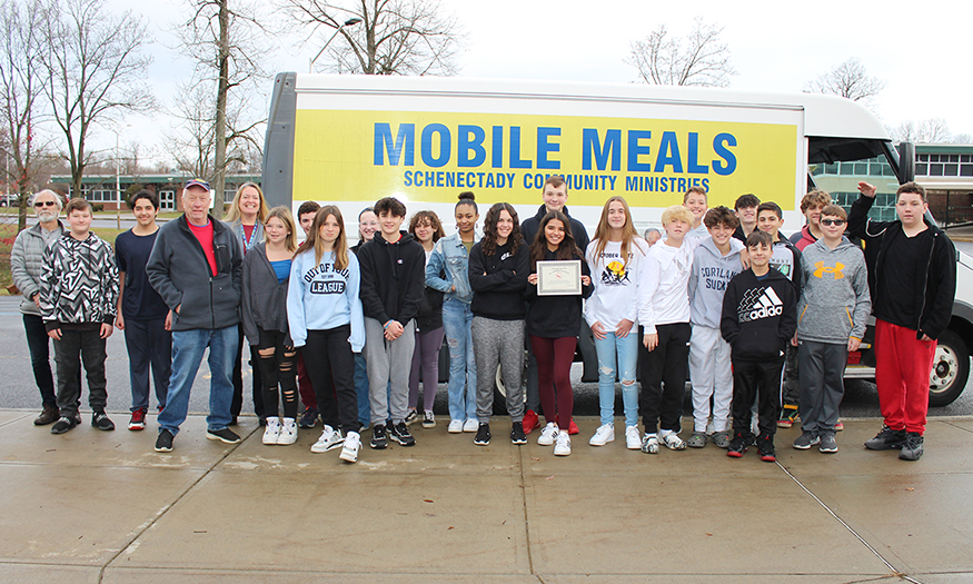 Students pose for photo in front of Mobile Meals van