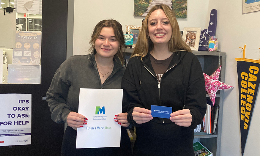 Students pose for photo holding college info