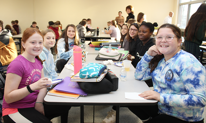 Students smile for a photo at lunch table