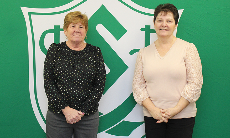 Two women pose for photo in front of Schalmont shield