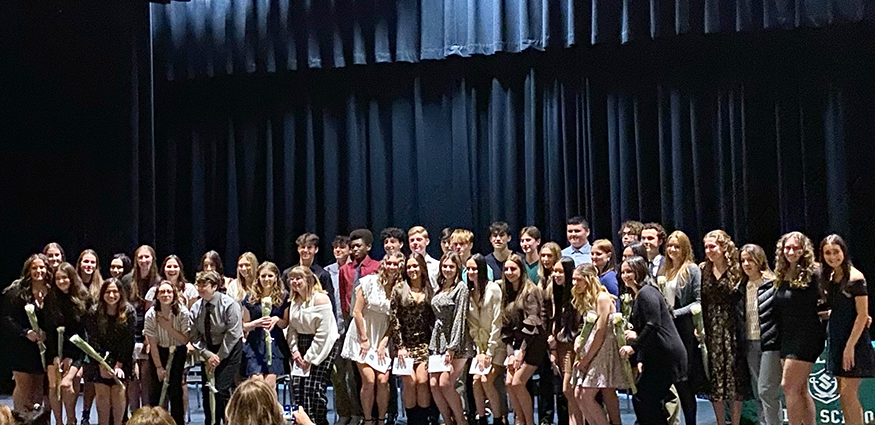 Large group of students pose for photo on auditorium stage