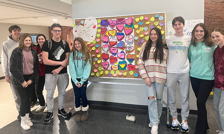 Students stand next to display board with notes