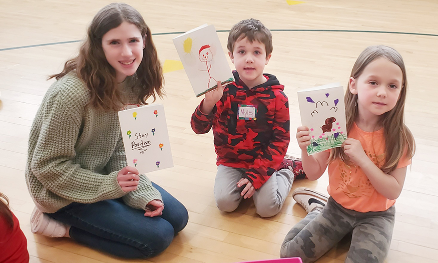 Students pose for photo with cards they made