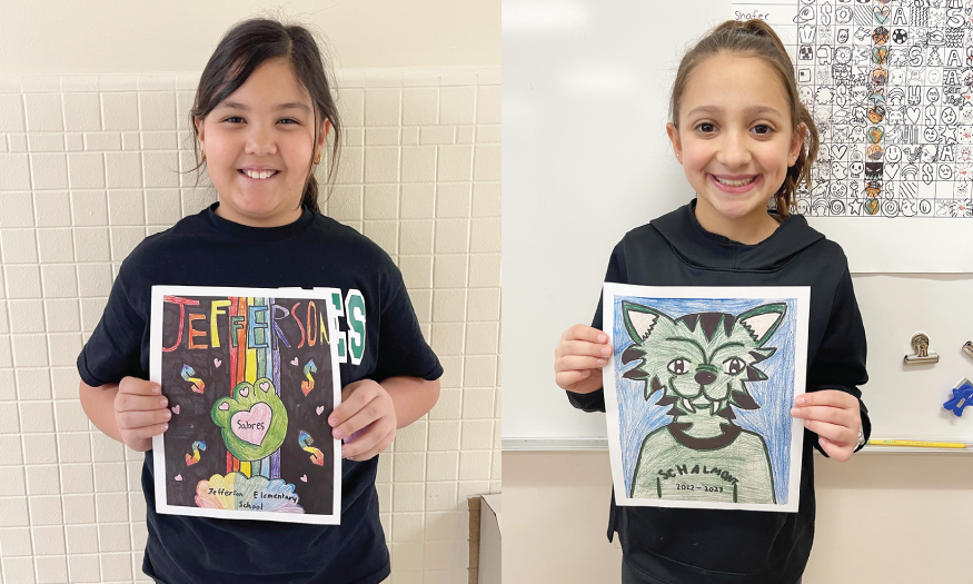 Two students pose for photos with artwork