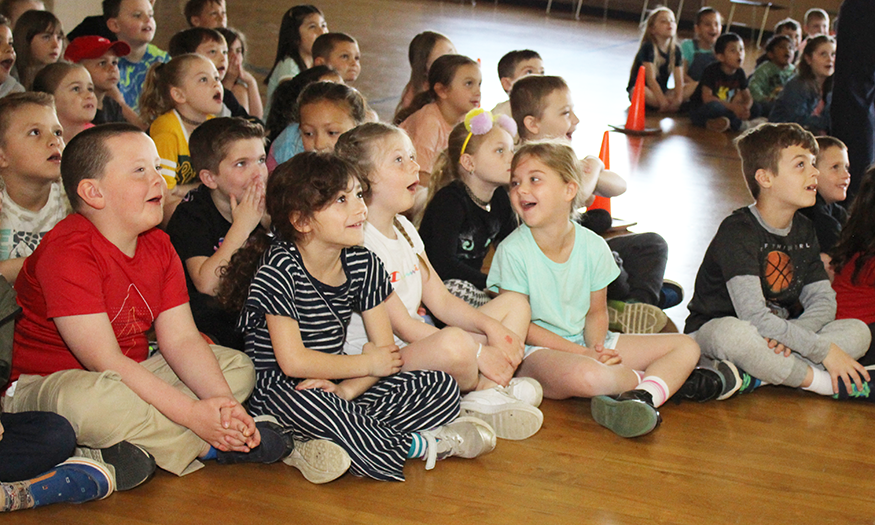 Students sit on floor smiling