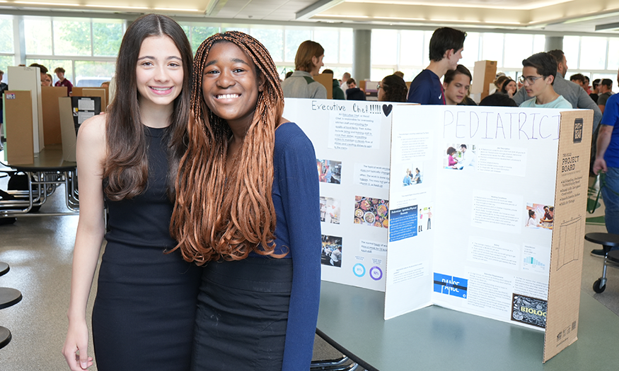 Students pose for photo in front of display