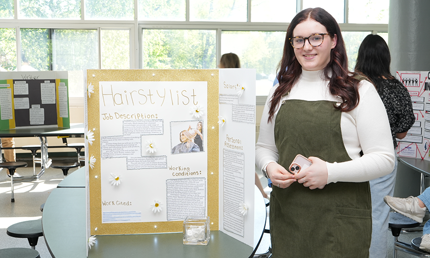 Student poses for photo in front of display