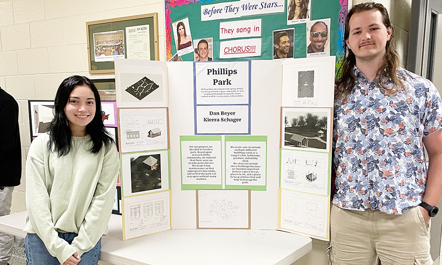 Students stand for photo in front of design plans