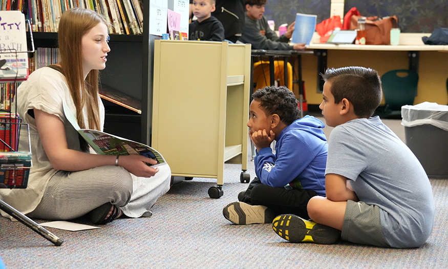 Students reads to other students on floor