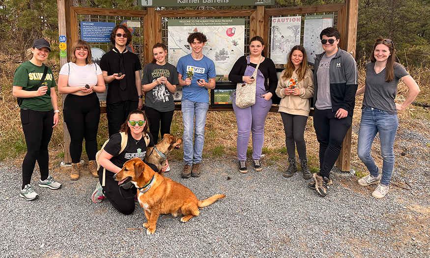 Students, teachers and dog pose for outdoor photo