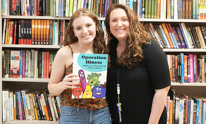Student holds book next to teacher
