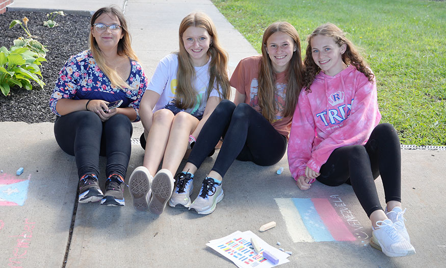 Group of students pose for photograph on sidewalk