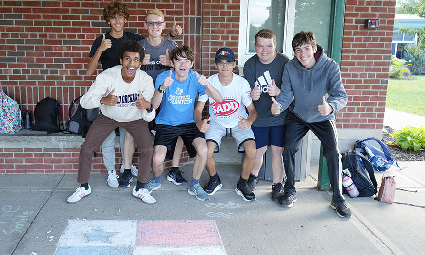 Group of students pose for photograph on sidewalk
