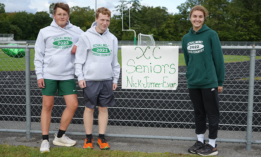 Seniors pose for photo besides sign