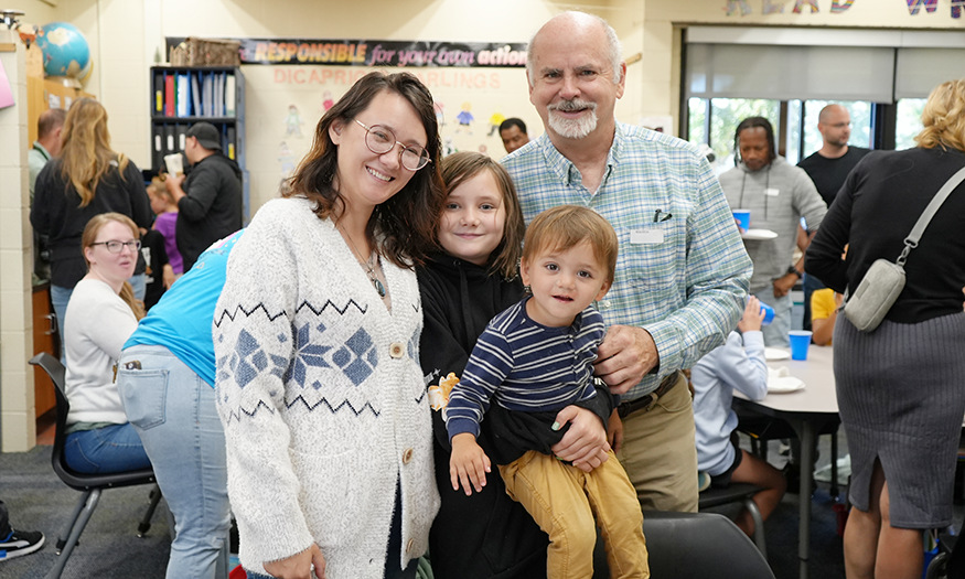 Family poses for photo in classroom