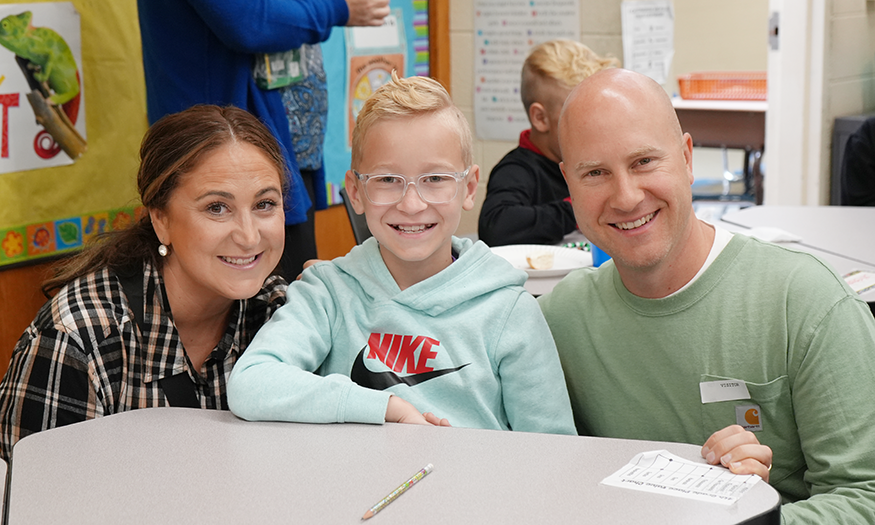 Family smiles for photo at desk