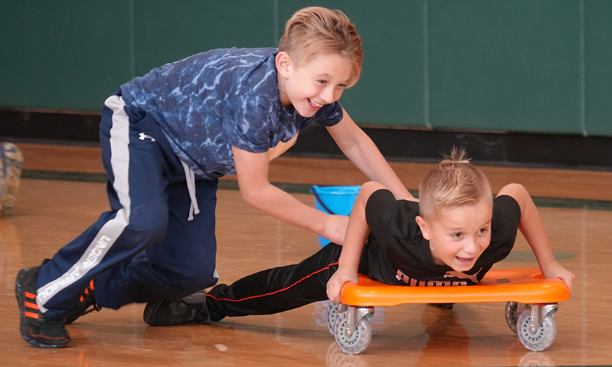 Students push each other on scooters