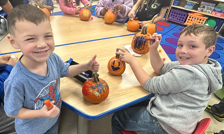 Students with pumpkins at desk