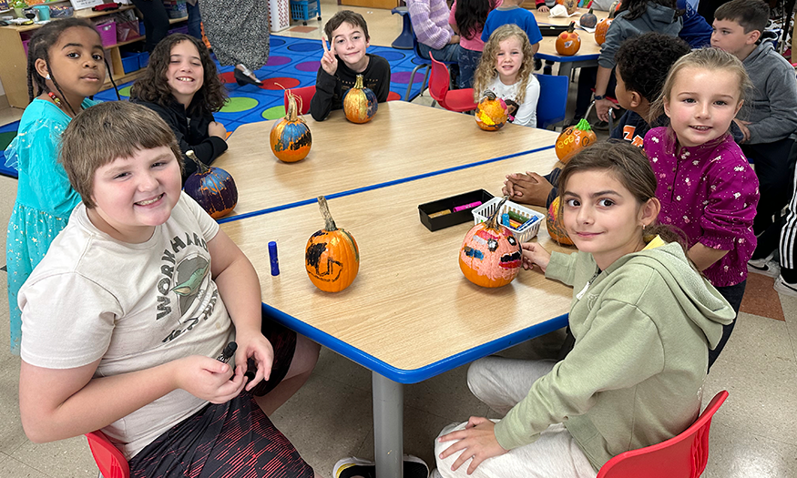 Students with pumpkins at desk