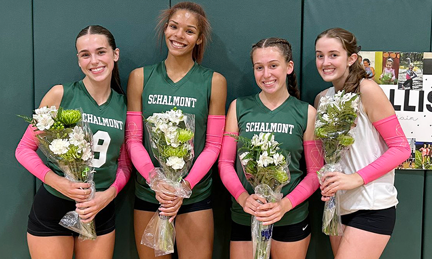 Four volleyball seniors hold flowers