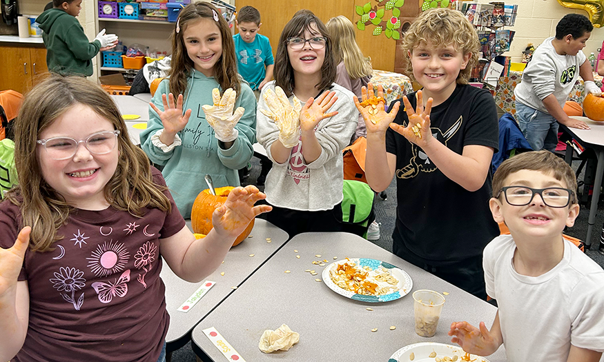 Students show hands with pumpkin innards