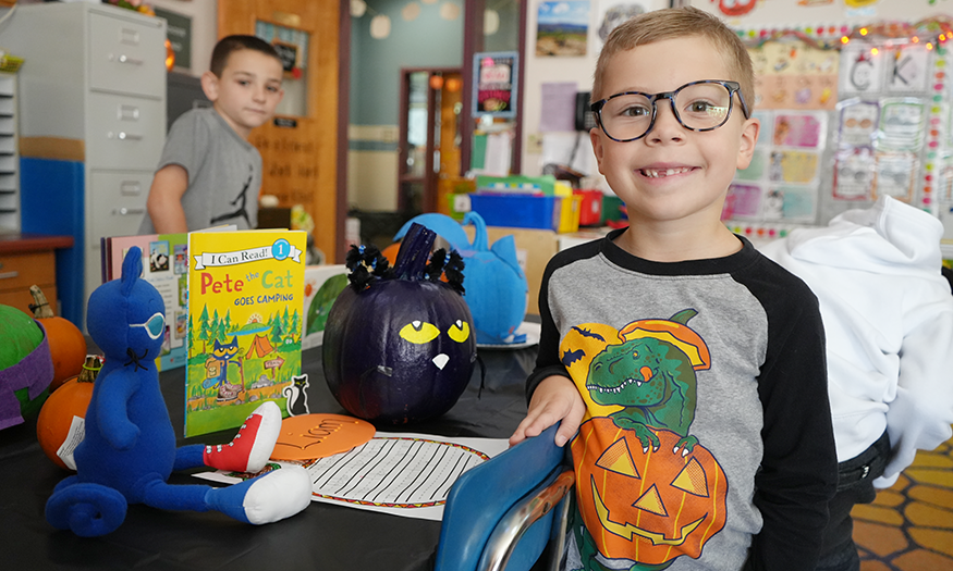 Student poses for photo with pumpkin