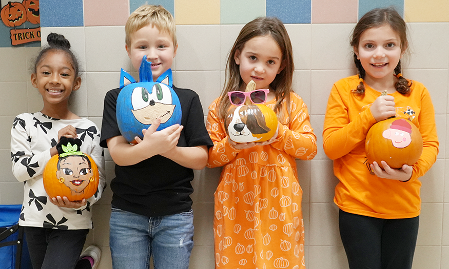 Students pose for photo with pumpkins