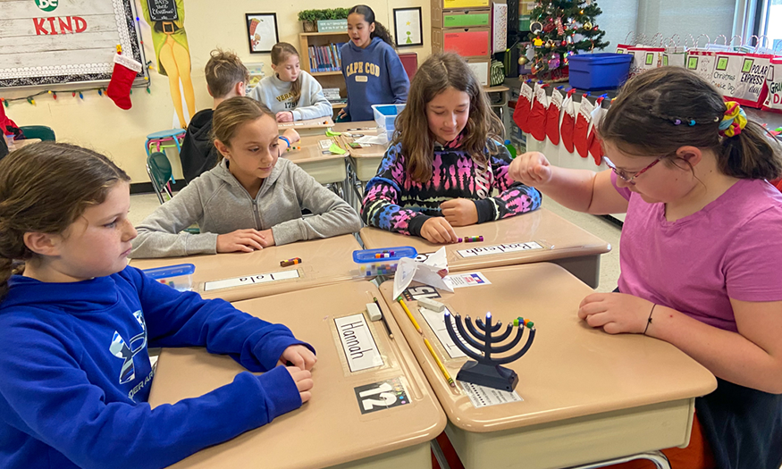 Students play dreidel game at desk