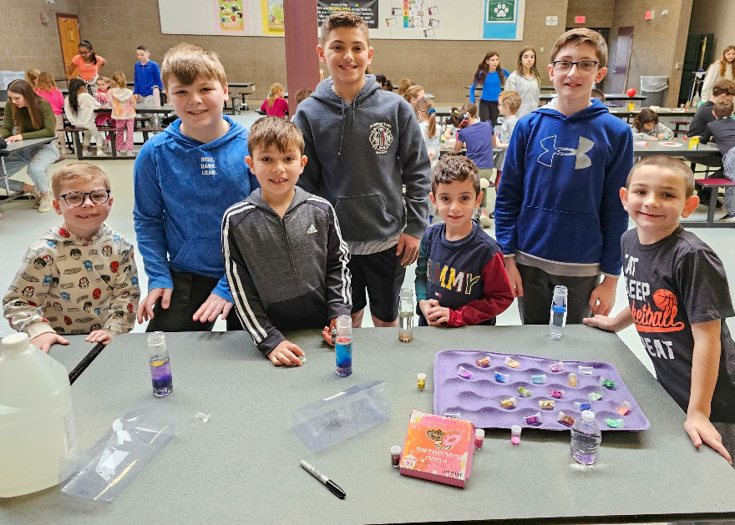 Students pose together behind table