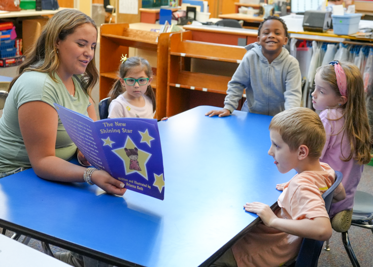 Students reads book to younger students