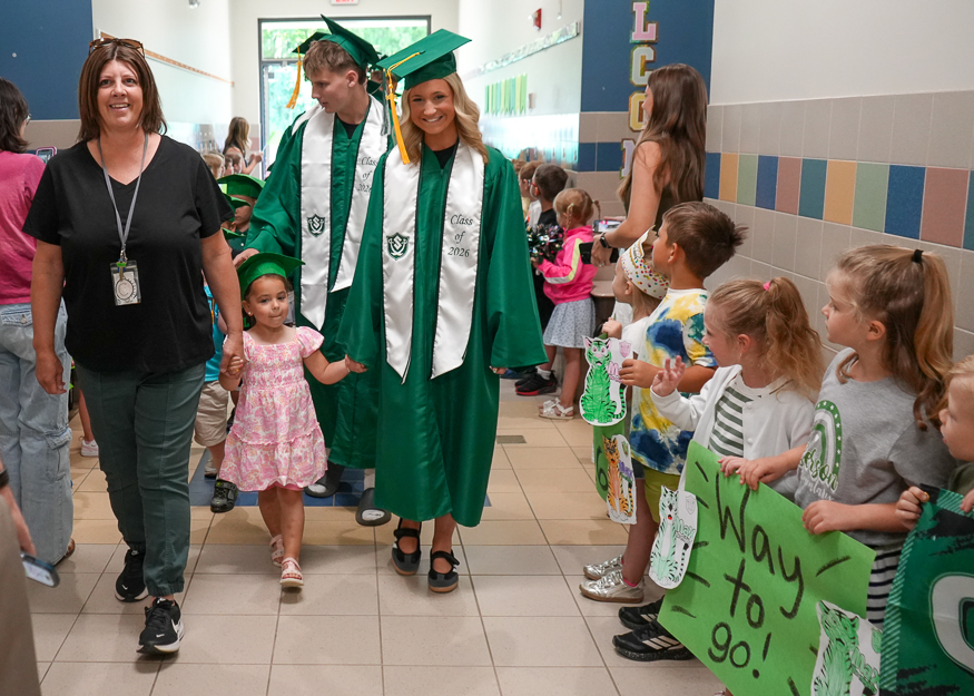 Senior and Pre-K student walk through hallway